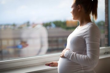Image of pregnant woman looking out of the window.