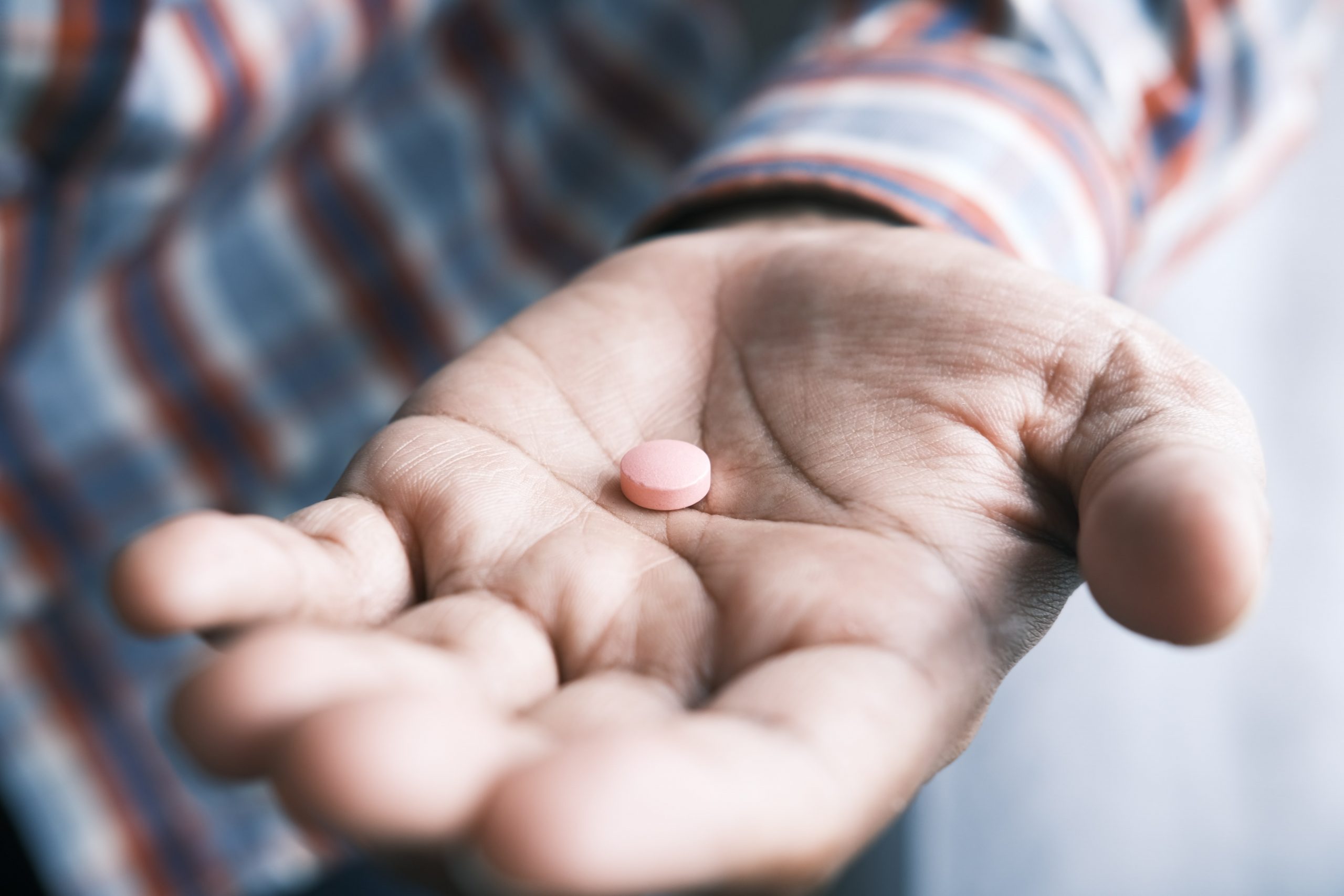Close up of man hand holding a pill.